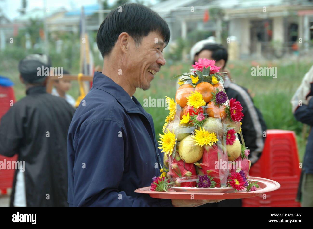 Un agricoltore porta un frutto che offre ad una cerimonia per ringraziare gli dèi presso un agriturismo biologico vicino a Hoi An, Vietnam. Foto Stock