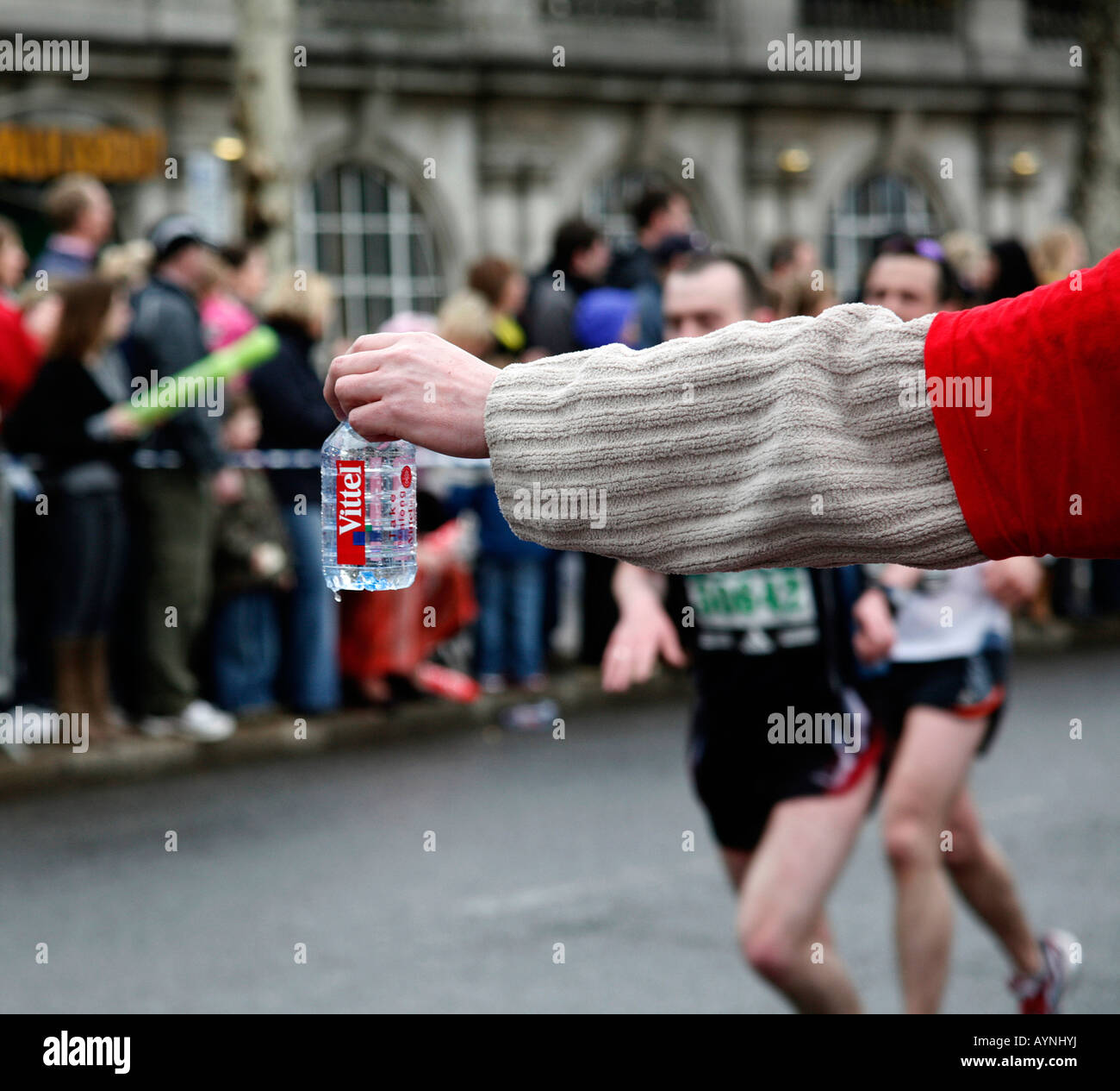 Una mano che offre acqua in bottiglia per i corridori nella maratona di Londra. Foto Stock