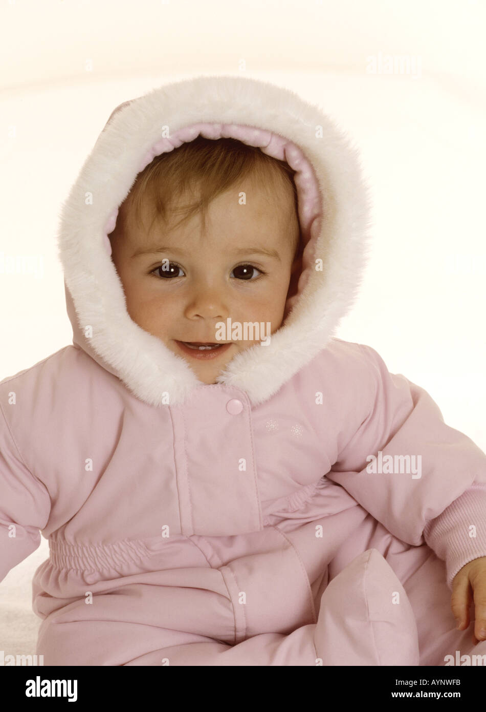 Baby girl peeping out di una pelliccia sorridente del cofano Foto Stock