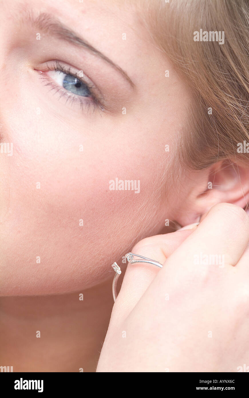 Frau steckt sich Ohrring un Foto Stock