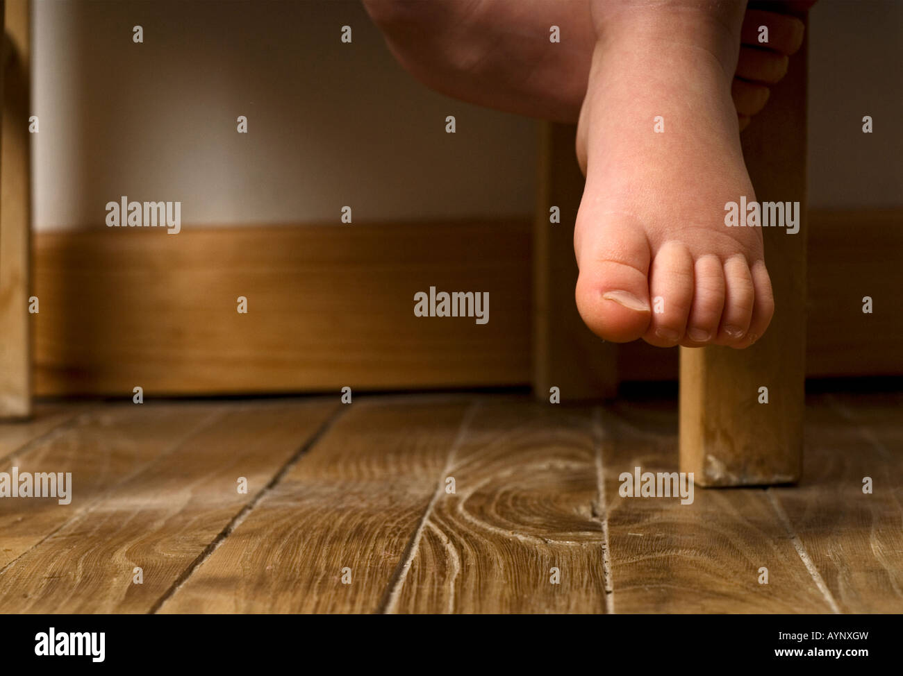 Foto di stock di un i bimbi a piedi nudi penzolante fuori una sedia Foto Stock