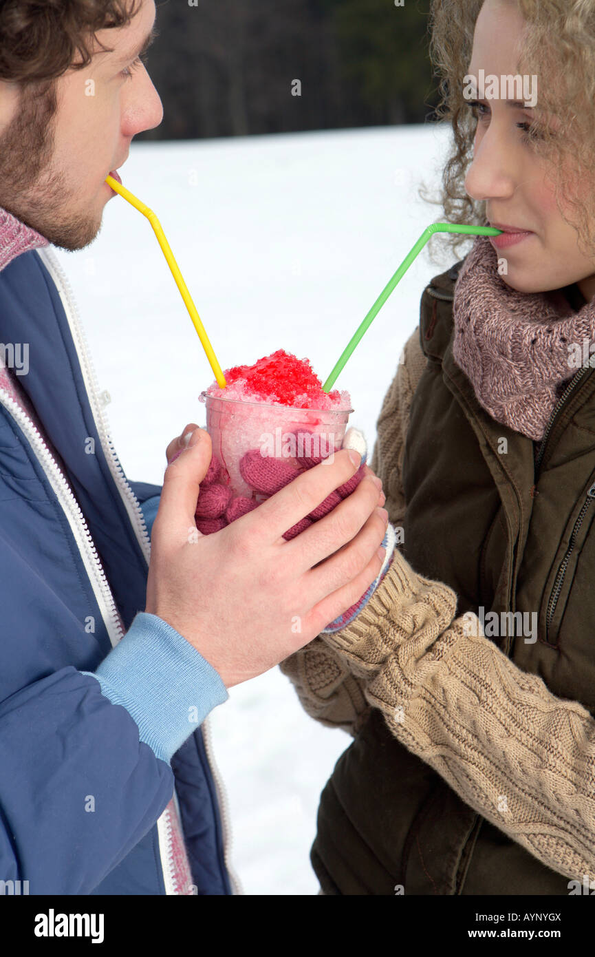 Giovane uomo e donna di bere ghiaccio frantumato dal medesimo bicchiere, close-up Foto Stock