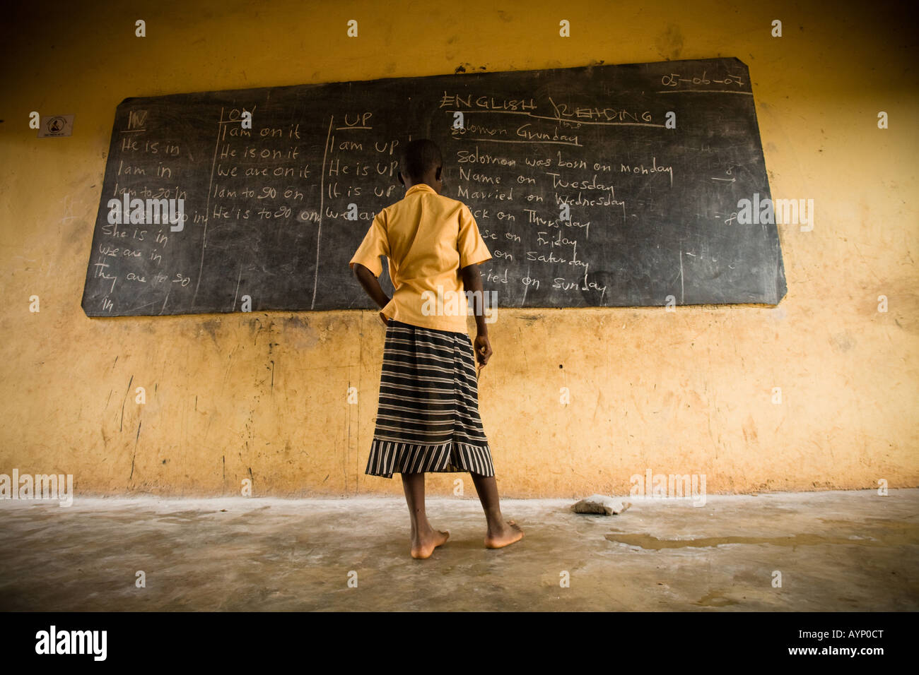 Una ragazza legge il testo scritto su una lavagna nera durante la classe al Nyologu scuola elementare nel villaggio di Nyologu del nord del Ghana Foto Stock
