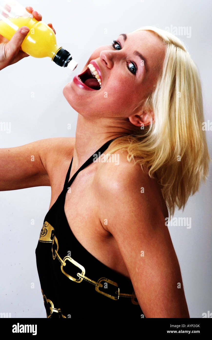 Donna bionda bere da una bottiglia di succo di frutta | Blond lachende Frau drinkt aus einer Saftflasche Foto Stock