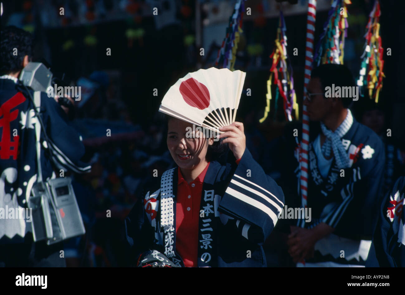 Giappone Honshu l'isola di Miyajima donna in autunno amore Festival mantenendo la ventola con il design della bandiera giapponese su di esso per il riparo dal sole. Foto Stock