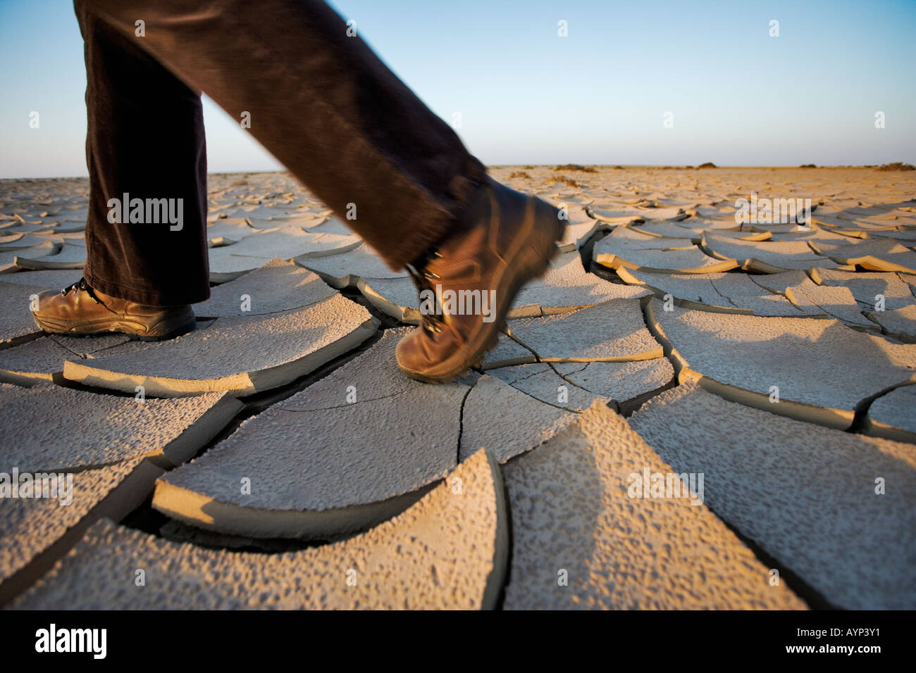 Persona con scarpe da trekking a piedi su incrinato fango secco nel deserto del Namib Foto Stock