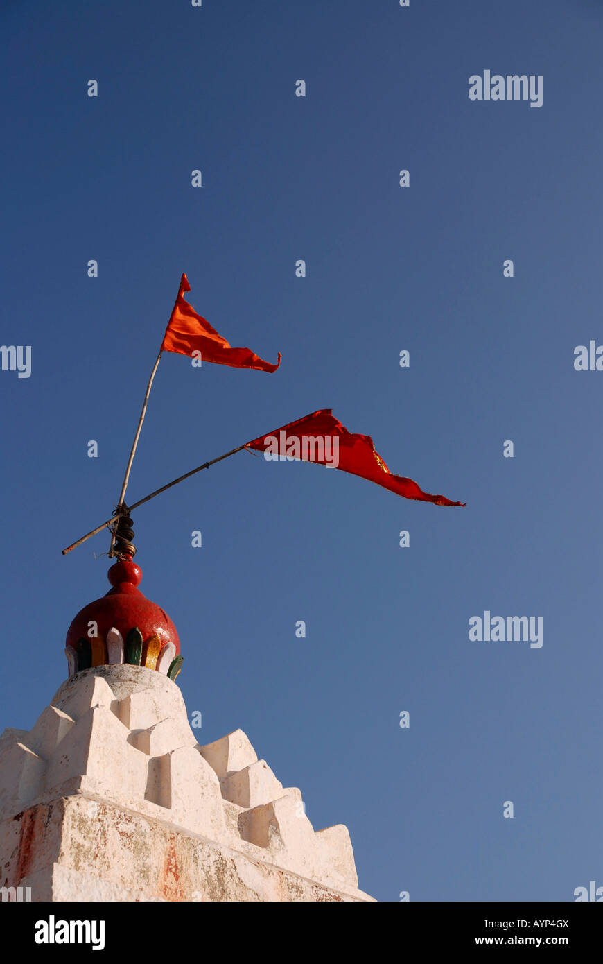 Bandiere rosse battono contro un cielo blu dalla parte superiore del imbiancato Hanuman tempio sulla collina Anjaneya Foto Stock