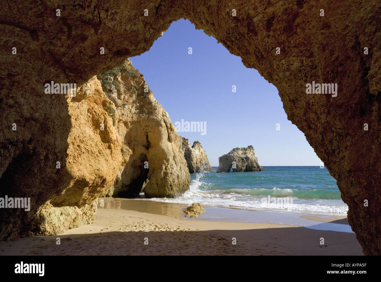 Il Portogallo Algarve la grotta in pareti rocciose a Alvor con mare calmo e la spiaggia Foto Stock