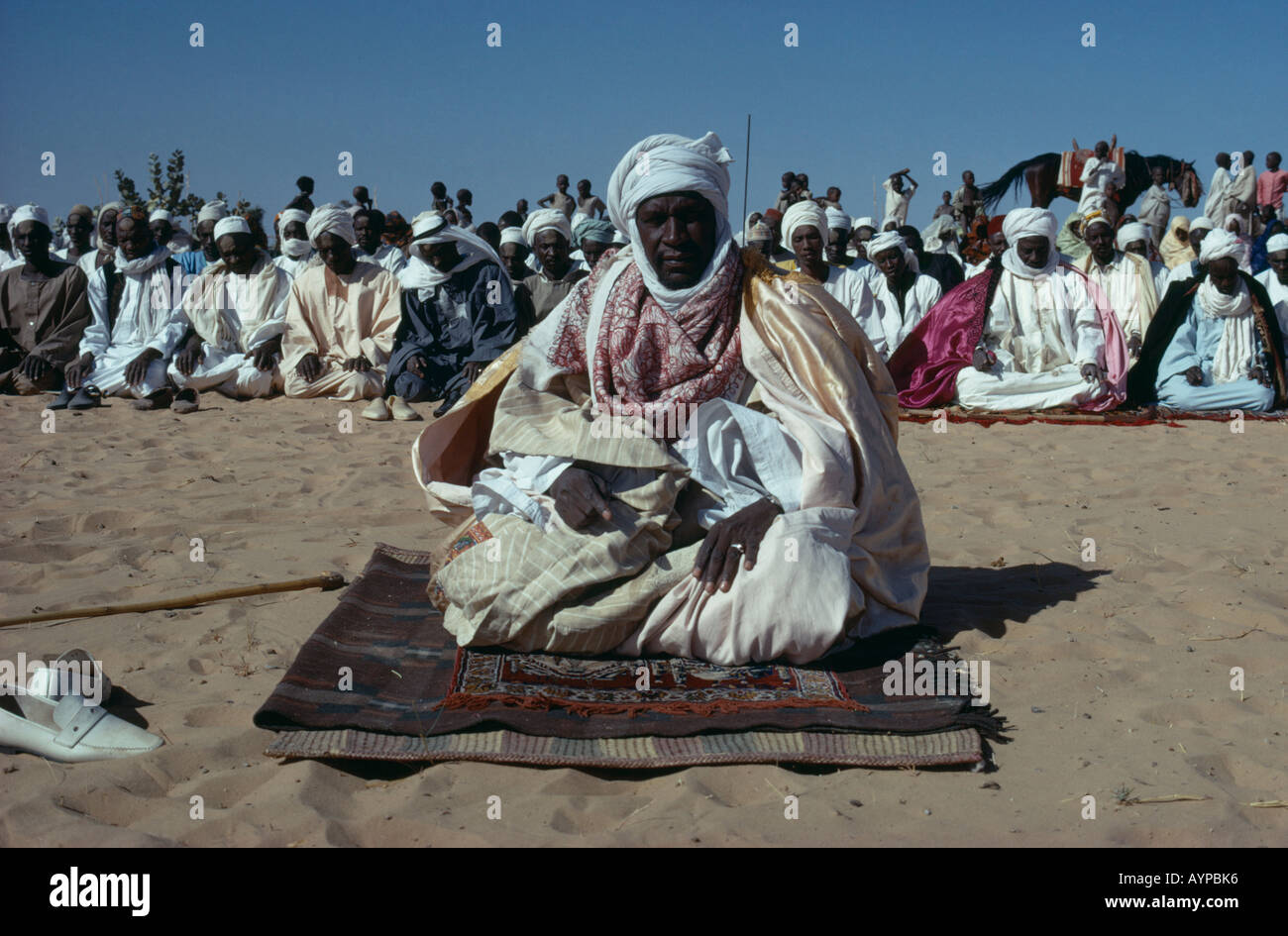 Il Ciad Centrafrica religione islam musulmani chief seduta sul suolo alla preghiera durante il festival circondato dalla folla di persone Foto Stock