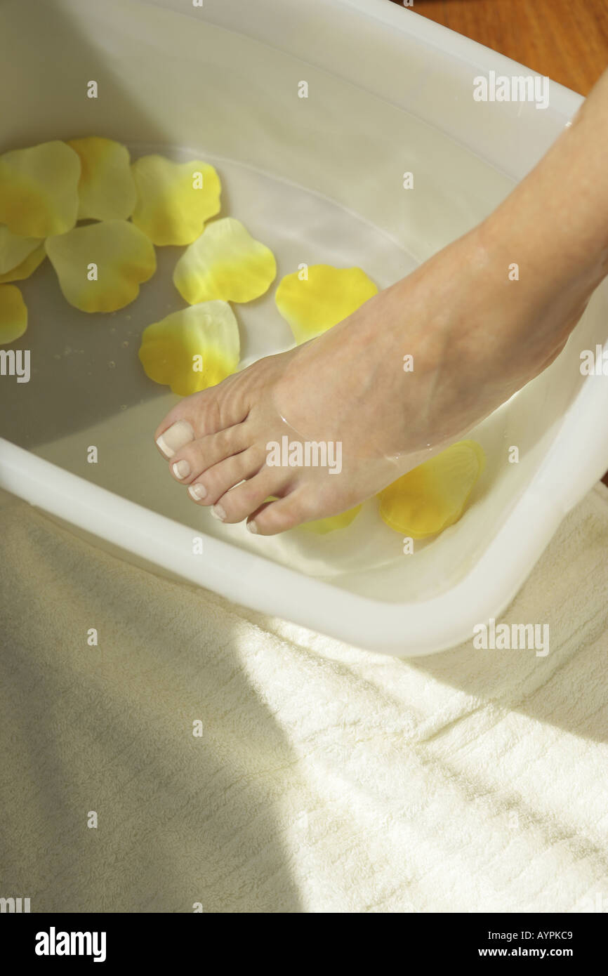 Elevato angolo di visione della donna piede sopra una vasca da bagno di petali gialli e acqua Foto Stock