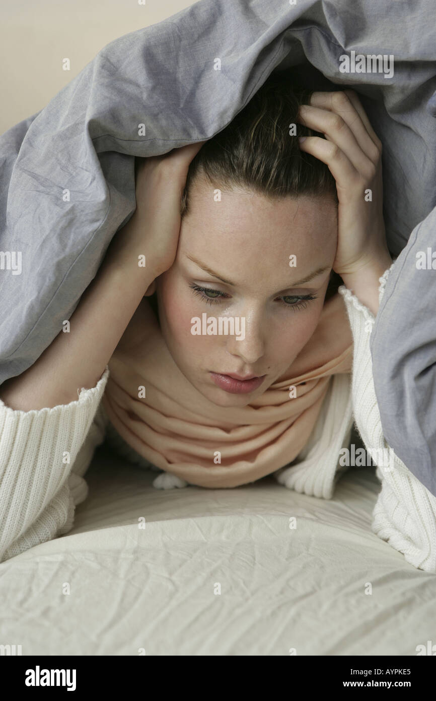 Una giovane donna nascondere se stessa al di sotto di una coperta Foto Stock