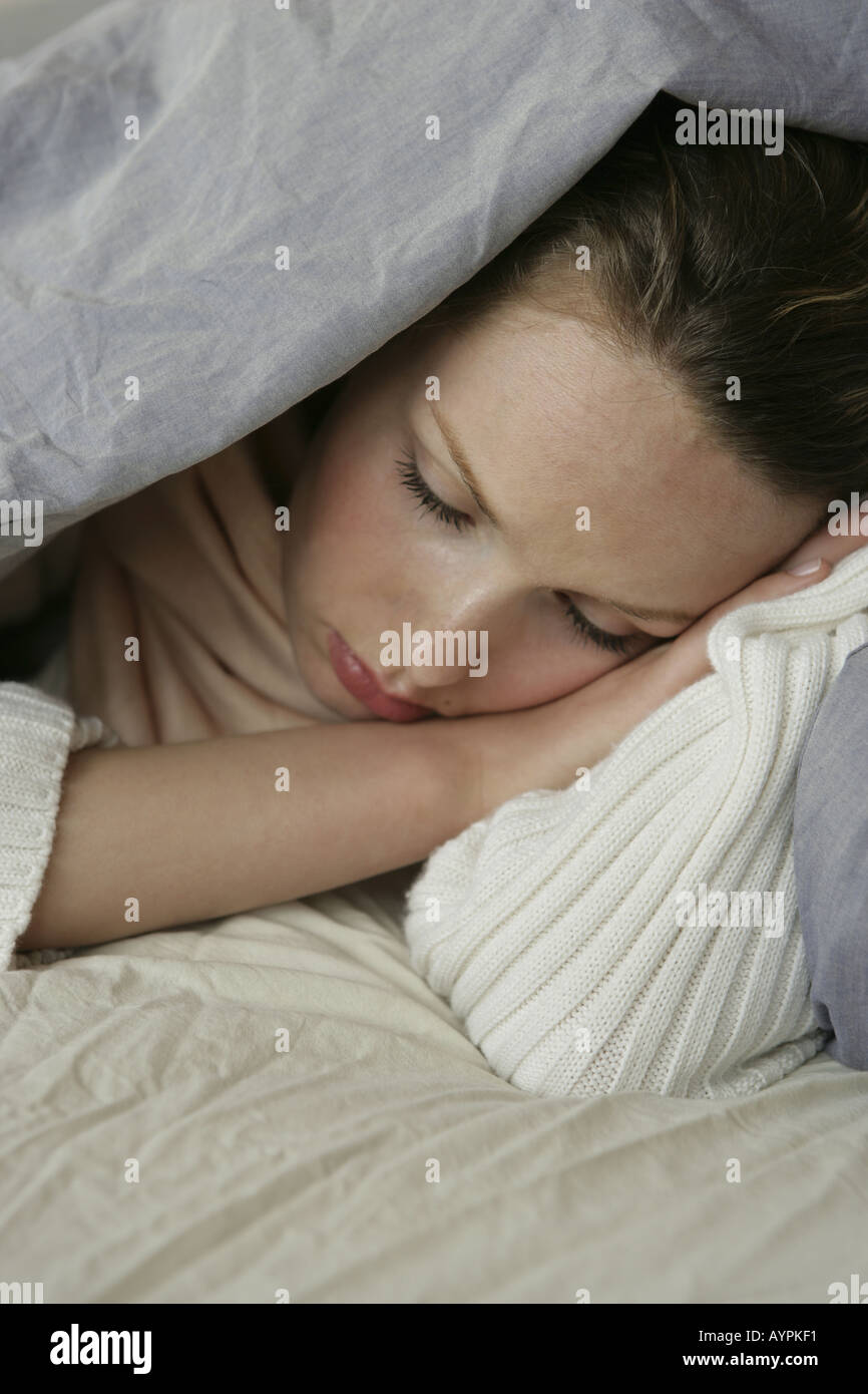 Una giovane donna che dorme sotto una coperta Foto Stock