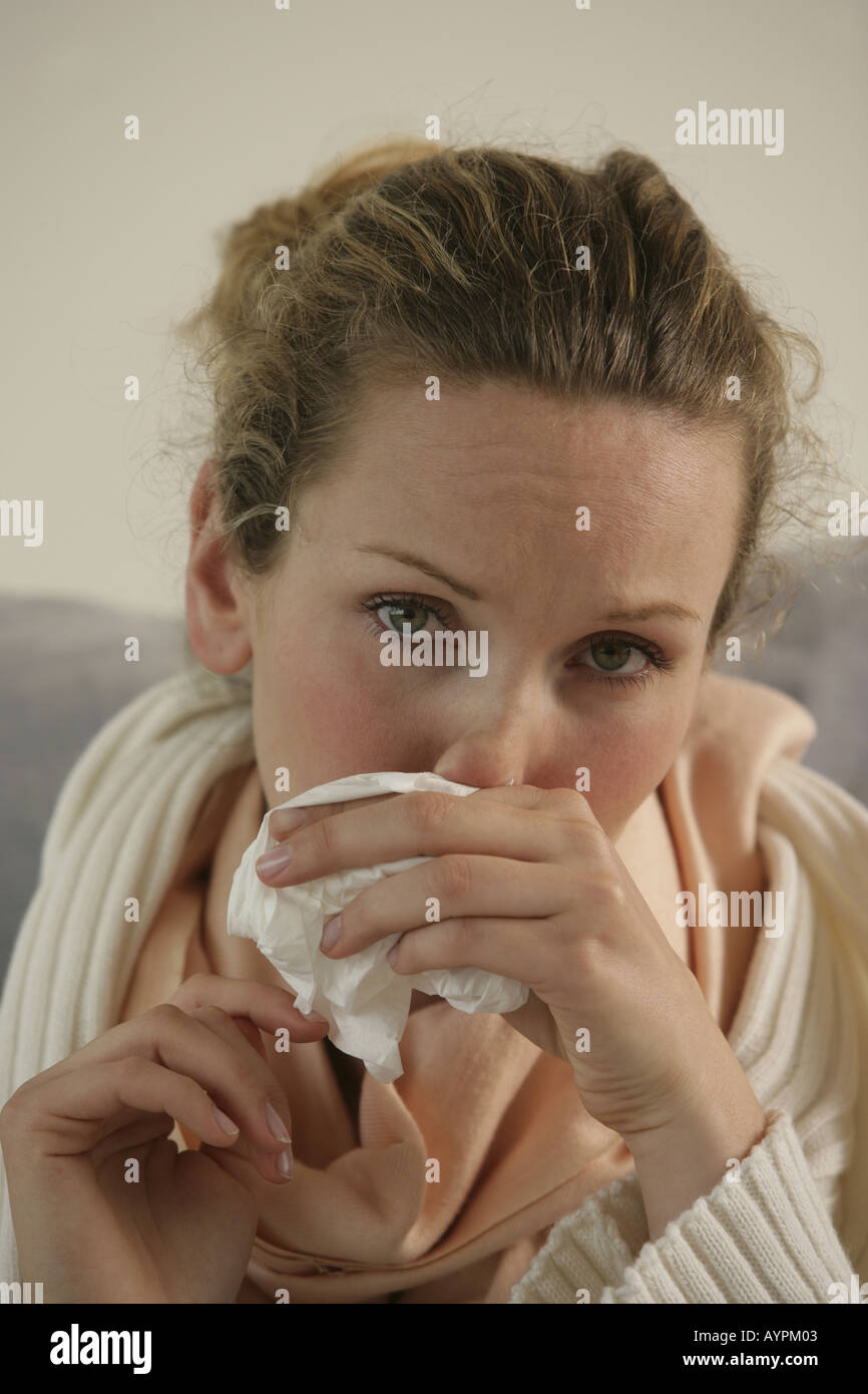 Una donna bionda tergi naso come lei soffre di raffreddore comune Foto Stock