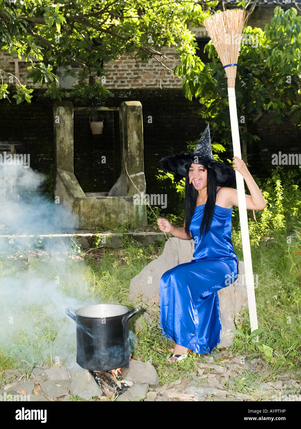 Giovani,bella strega in vestito blu e sottolineato hat getta incantesimi in un giardino,Madiun,East Java,l'Indonesia. Foto Stock