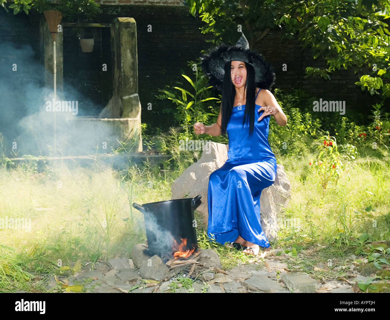 Giovani,bella strega in vestito blu e sottolineato hat getta incantesimi in un giardino,Madiun,East Java,l'Indonesia. Foto Stock