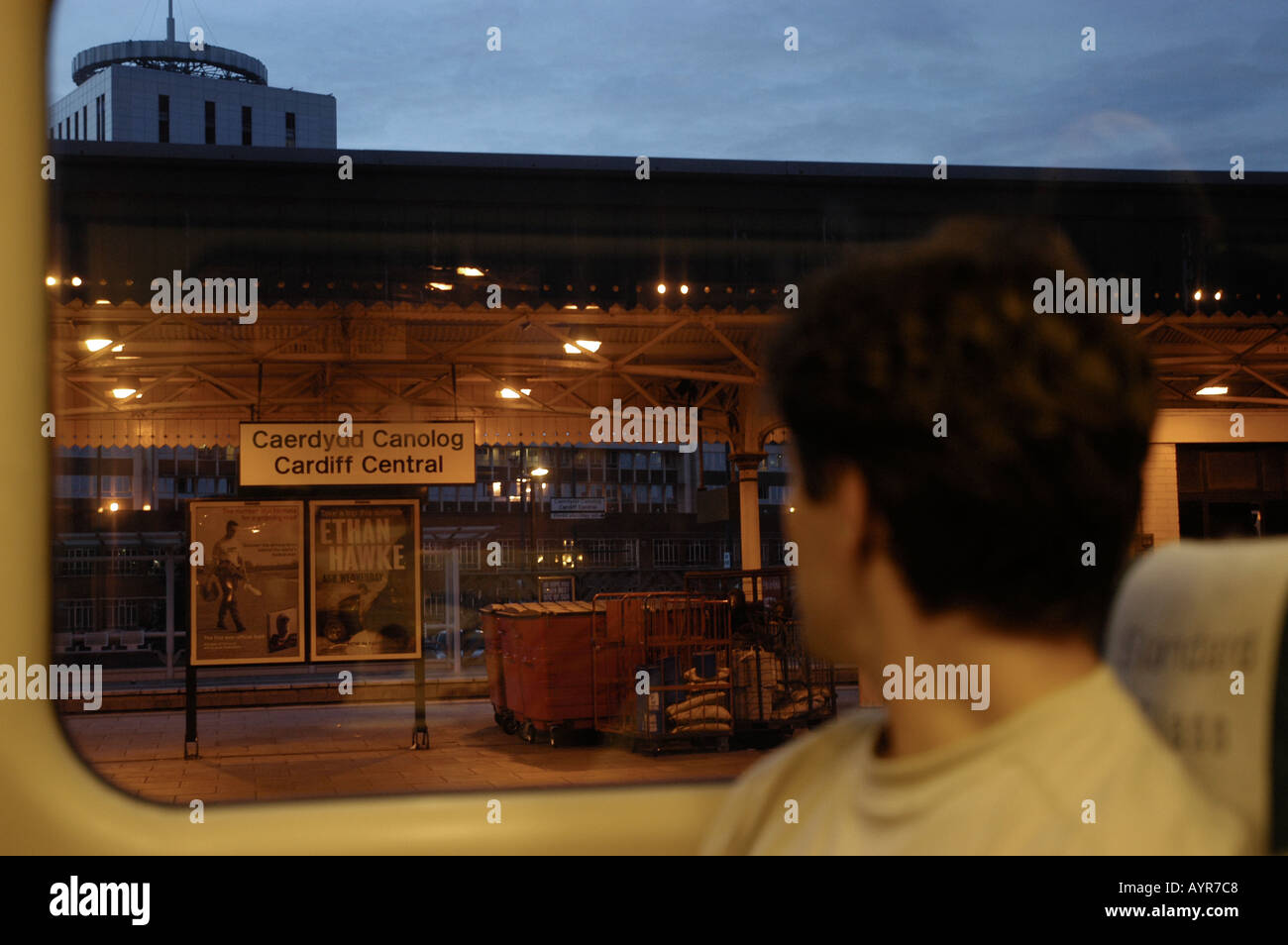 L'uomo all'interno del treno guardando attraverso la finestra sulla la stazione centrale di Cardiff Wales UK Foto Stock