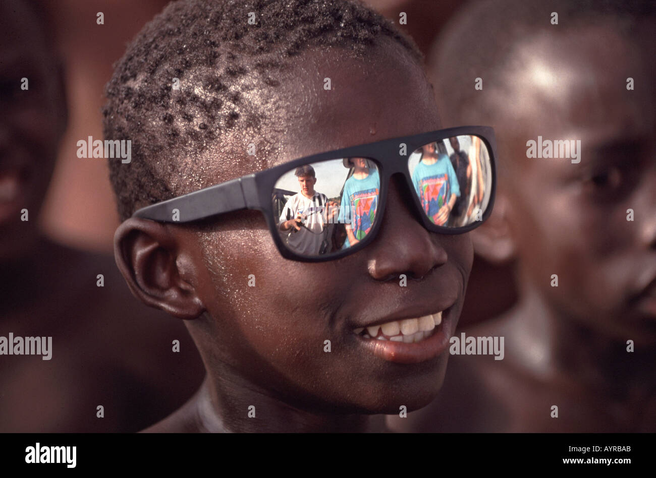 Bambino con occhiali da sole in Gambia Africa Occidentale guardando gli scolari provenienti da Inghilterra Foto Stock