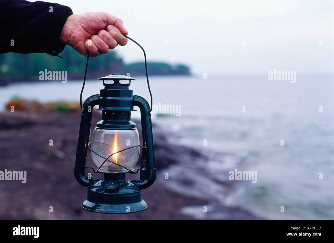 Man mano che trattiene il gas liquido lanterna di carburante sul roccioso riva del lago Superior Minnesota MN USA Foto Stock