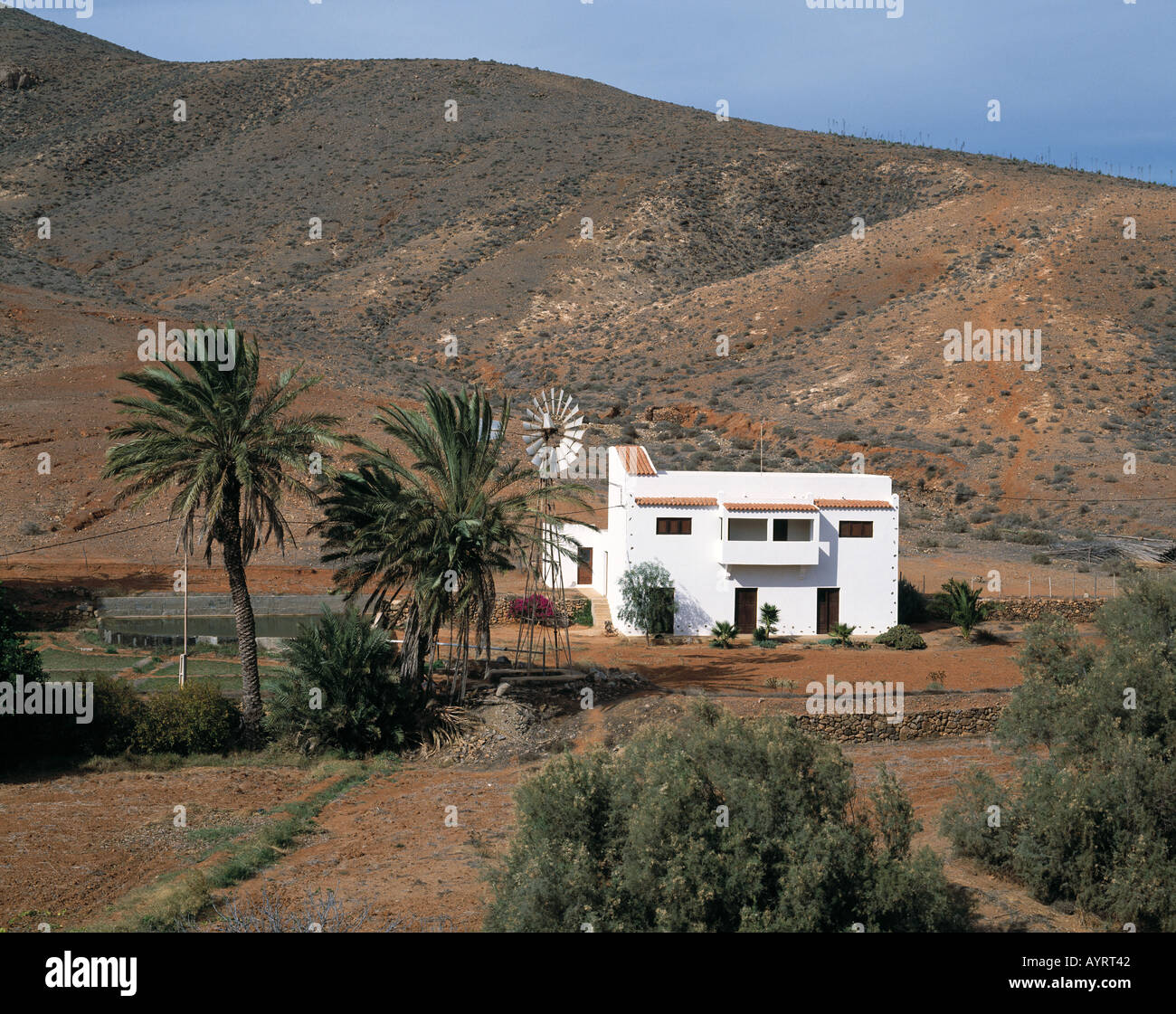 Huegelige Landschaft, Berglandschaft kahle, oasenaehnliches Tal, Offenburg, freistehendes Haus, Windrad, Betancuria, Fuerteventura, Kanarische isole Foto Stock