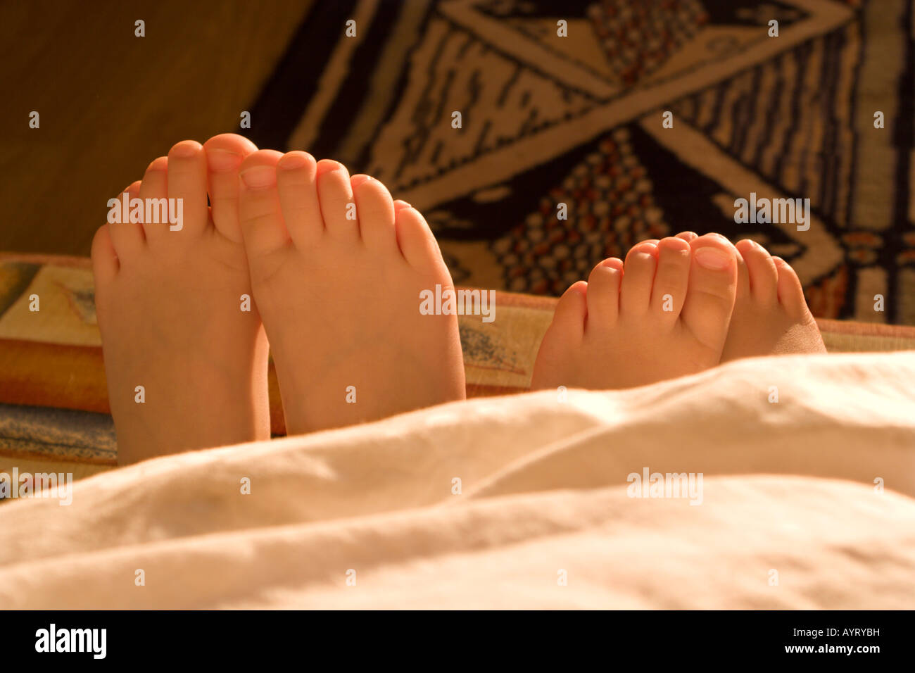 Donna adulto e bambino i piedi che spuntavano da sotto una coperta Foto Stock
