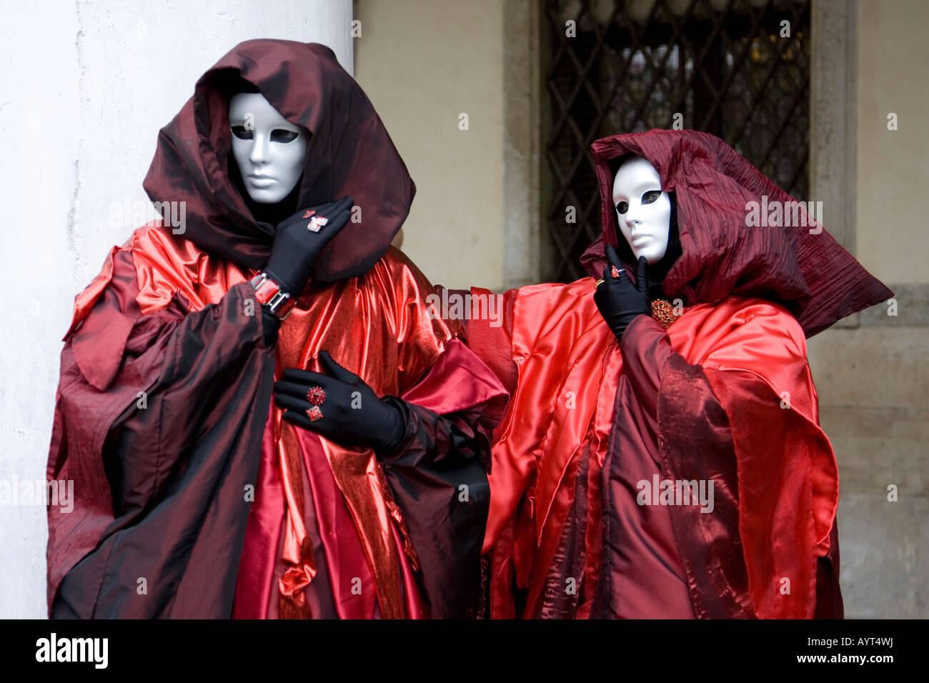 Due persone che indossano rosso-nero costumi, incappucciati mantelli e maschere, il Carnevale di Venezia il Carnevale di Venezia, Italia Foto Stock