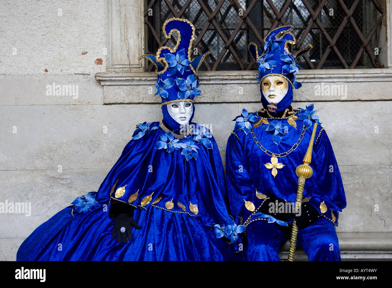 Due persone che indossano costumi blu e maschere seduta su una panchina di fronte a una finestra, il Carnevale di Venezia il Carnevale di Venezia Foto Stock