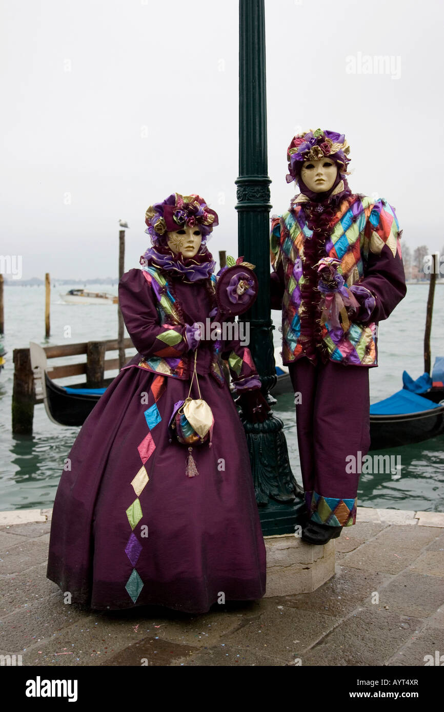 Due persone che indossano viola costumi e maschere in piedi nella parte anteriore delle gondole, Carnevale di Venezia il Carnevale di Venezia, Italia Foto Stock