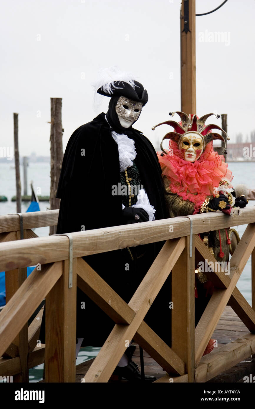 La gente vestita di nero-e-bianco e rosso costumi e maschere in piedi su un dock, il Carnevale di Venezia il Carnevale di Venezia, Italia Foto Stock