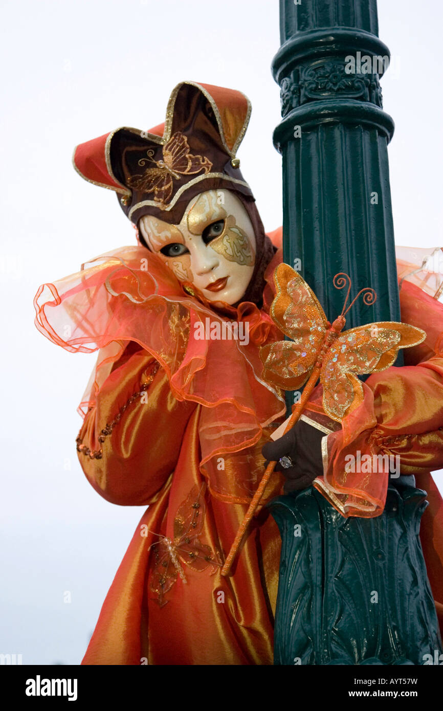 Harlequin arancione (buffone di corte) Costume e Maschera accanto a lampione, il Carnevale di Venezia il Carnevale di Venezia, Italia Foto Stock
