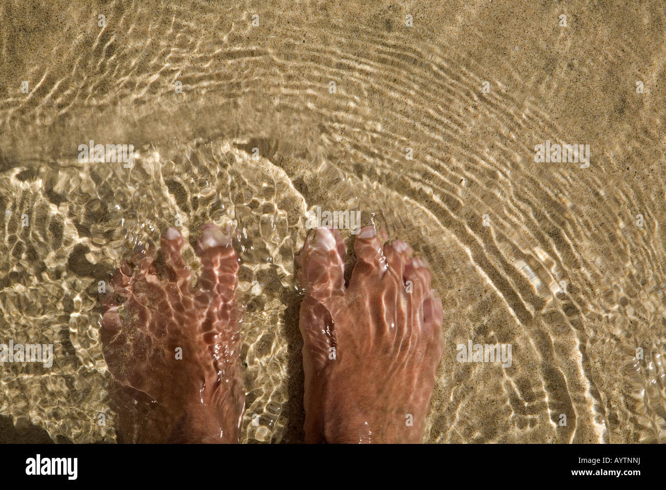 Due piedi sulla sabbia sotto l'acqua di mare Foto Stock