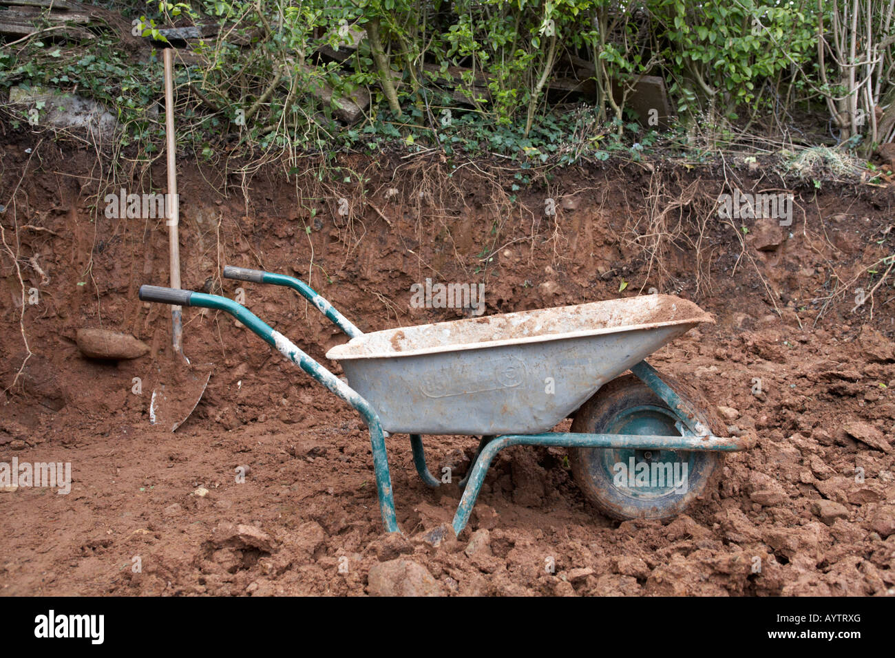 Carriola e vanga nel giardino sterri scavo come parte del lavoro di costruzione con strumenti come progetto nazionale per la fondazione Foto Stock