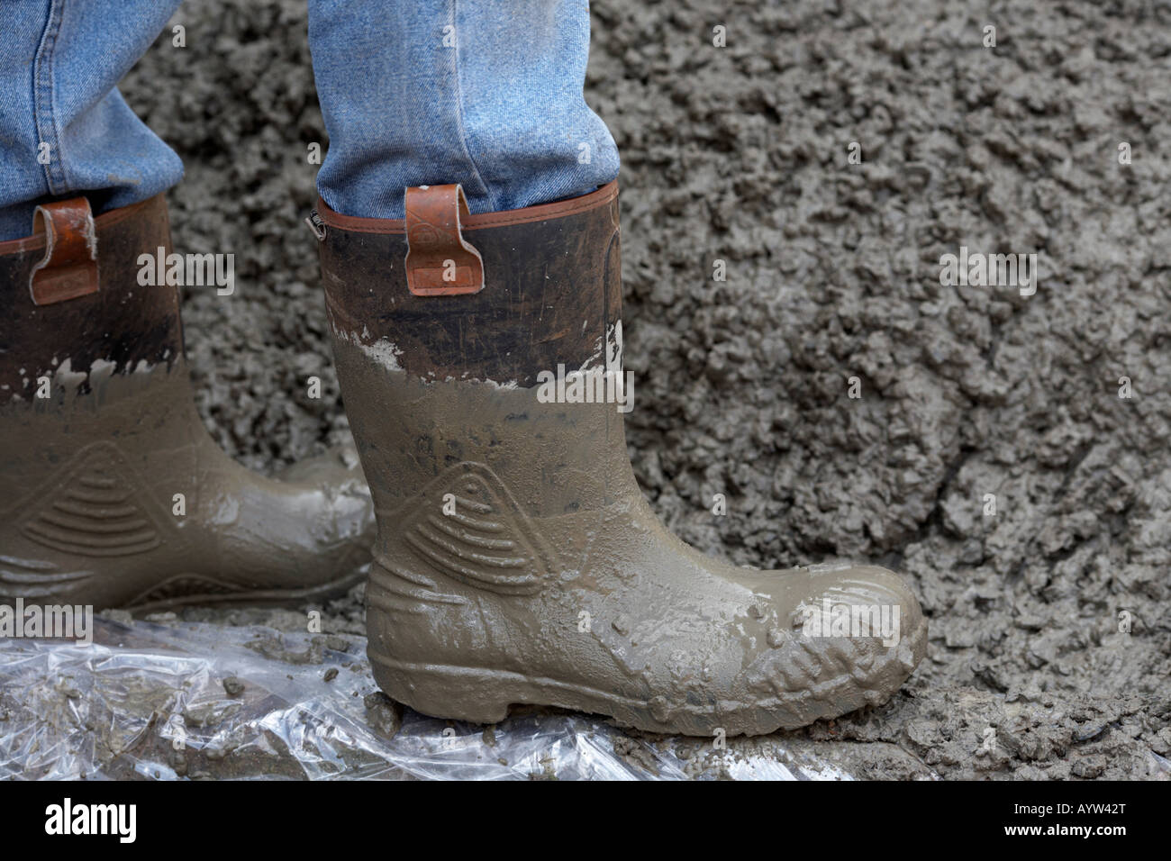 Workman indossa le cuffie di protezione e jeans mentre la posa di base in cemento Foto Stock