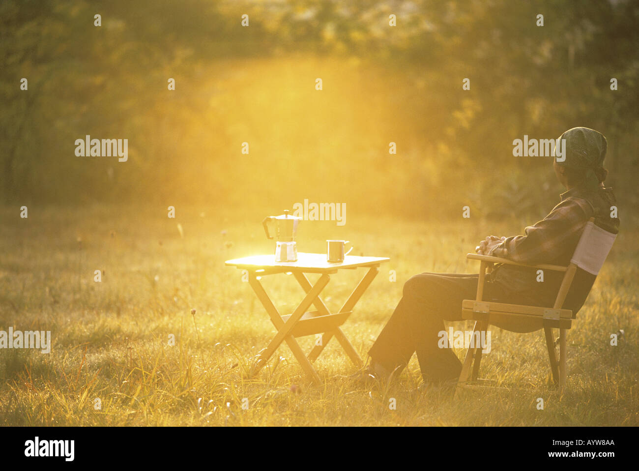 Uomo con caffè caldo seduto su una sedia in giardino Foto Stock