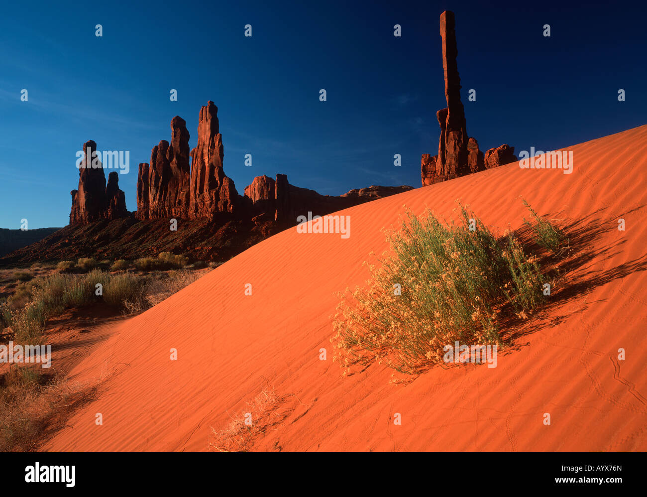 Con imponenti formazioni rocciose come sfondo, una grande duna di sabbia spazza Monument Valley in Arizona Utah confine. Foto Stock
