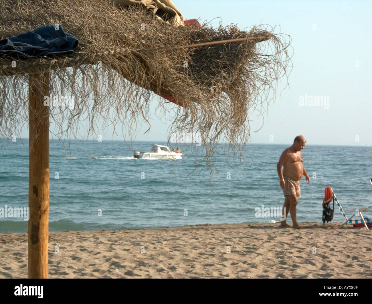 L'uomo, il motore di lancio, scartato i vestiti, ombrellone, Carvajal beach, Fuengirola,Costa del Sol, Spagna Foto Stock