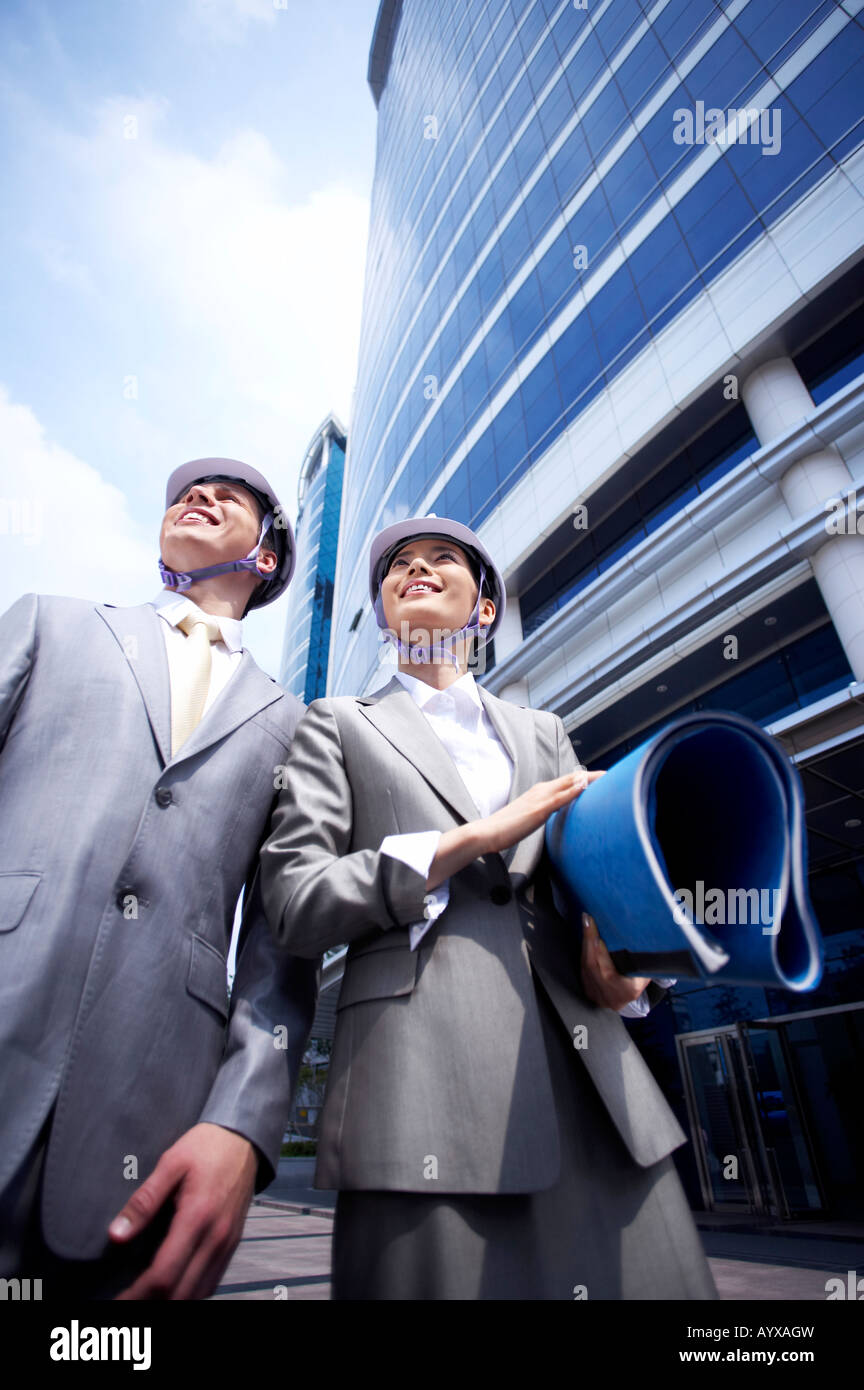 Uomo e donna con casco di sicurezza su cercando nello stesso posto Foto Stock