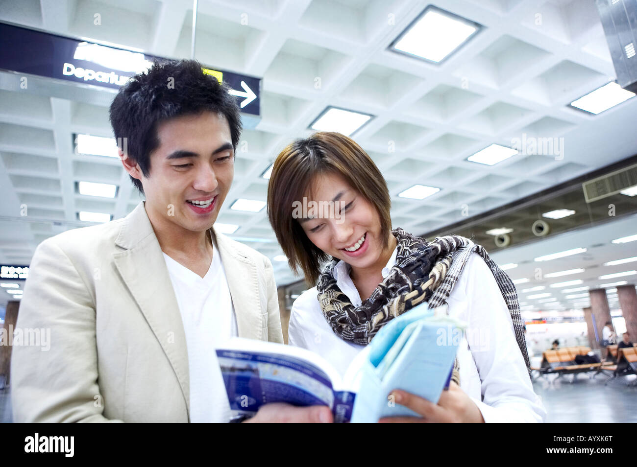 Una coppia sorridente con vedendo un phamplet in aeroporto Foto Stock
