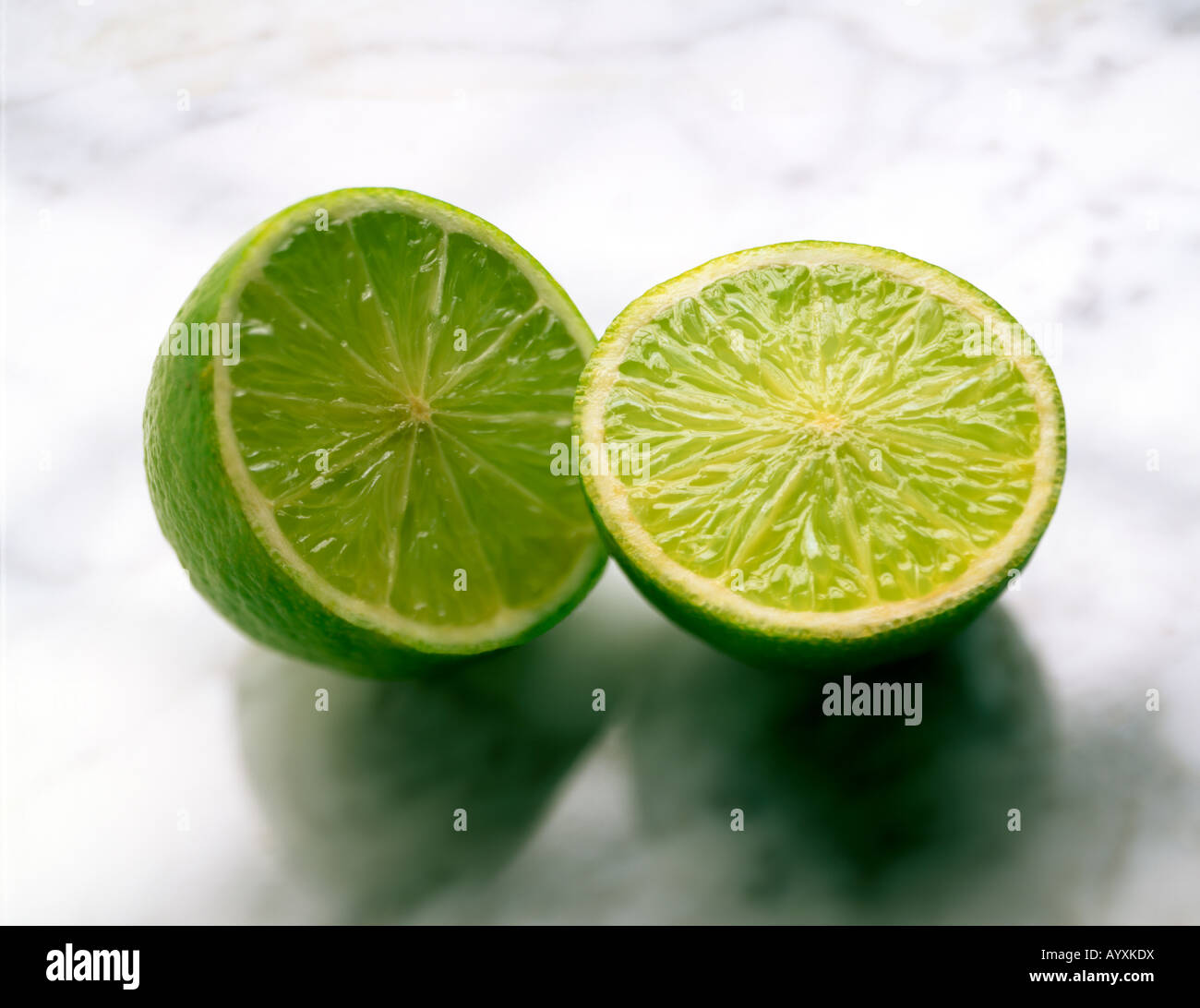 Inquadratura di un intero lime tagliato a metà su un piano di marmo Foto Stock