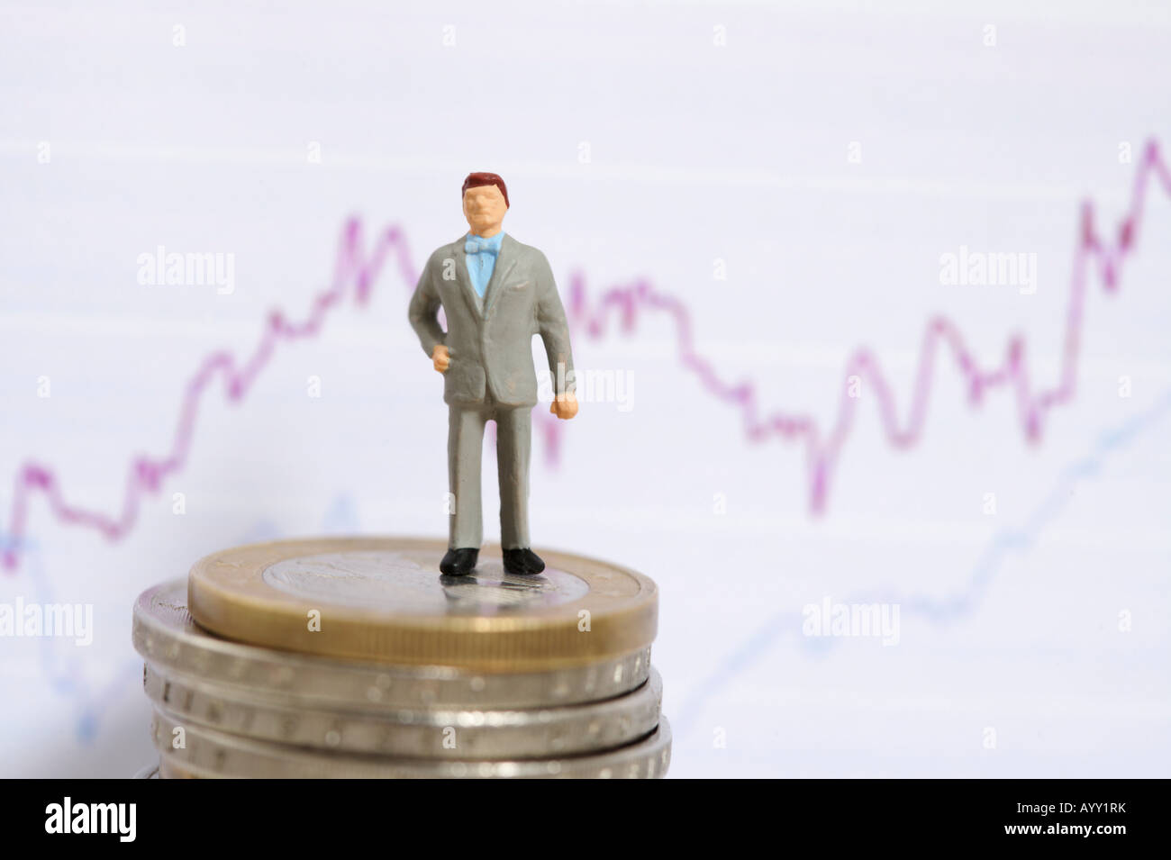 Imprenditore figurina su una pila su monete, linea grafico in background Foto Stock