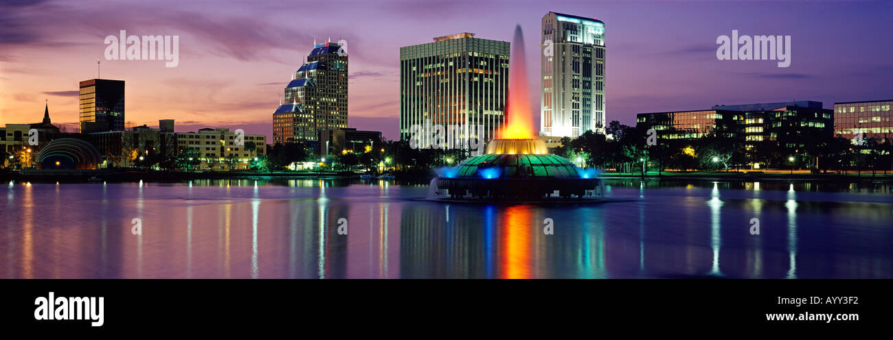 Con incandescente tramonto come sfondo downtown Orlando FL è riflessa nella liscia mirror Lake Eola Foto Stock