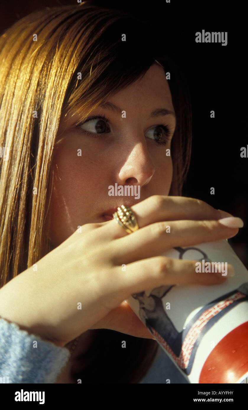 Ragazza adolescente soda bere dal bicchiere di carta utilizzando una paglia Foto Stock