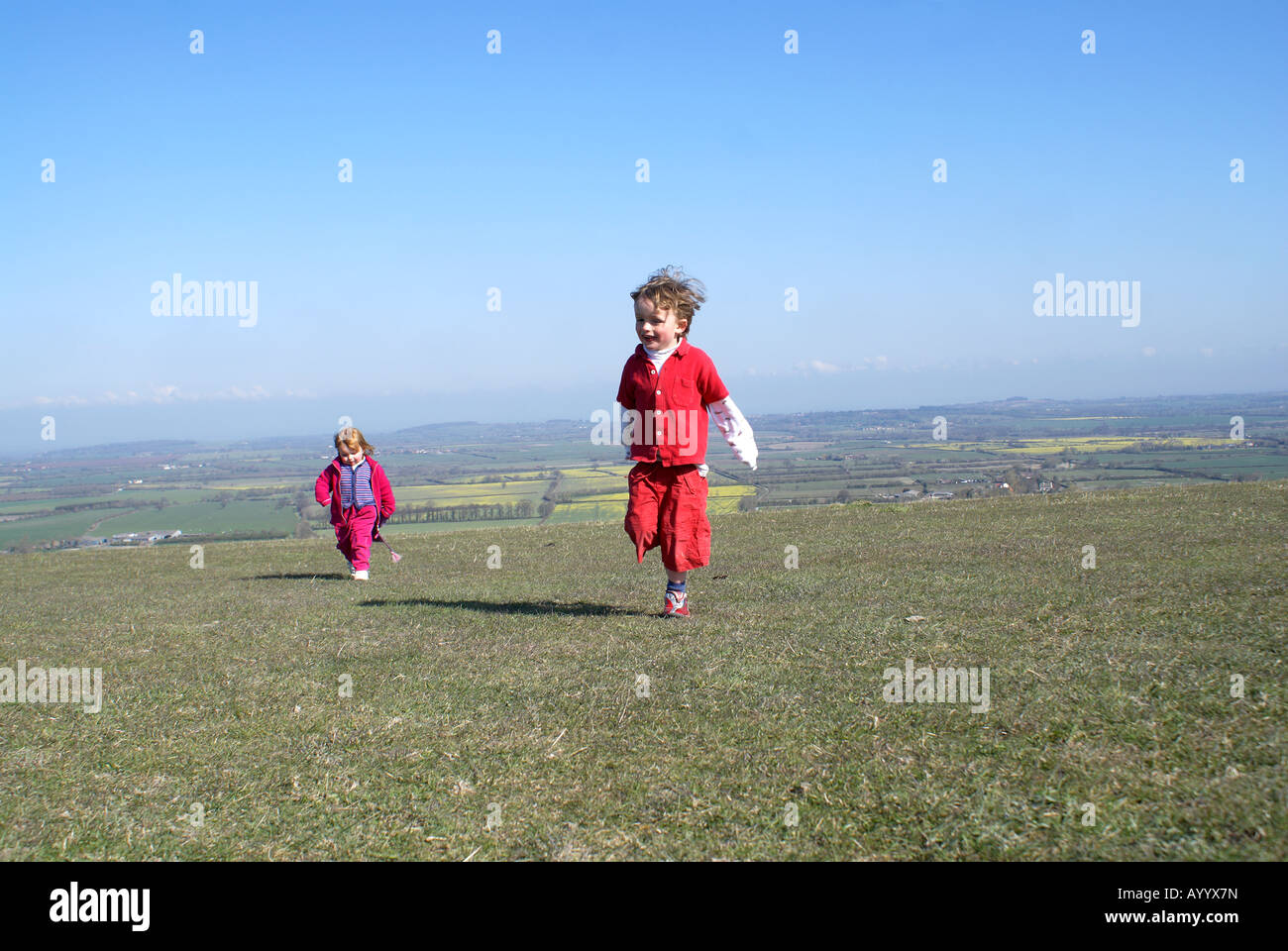 'Running free'tre anni di old boy e sorella godendo della libertà di downs sopra Oxfordshire Foto Stock