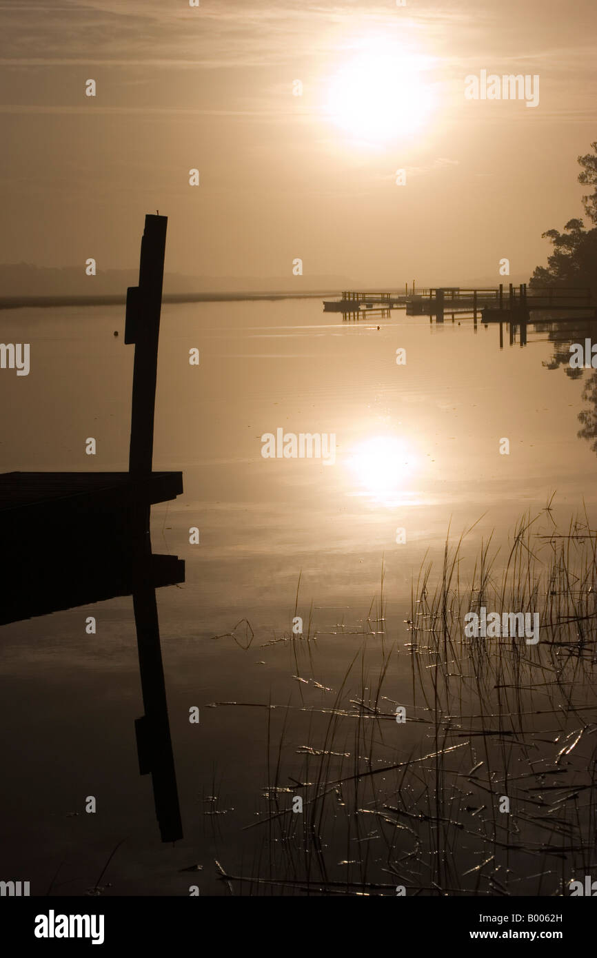 I primi di dicembre sole di mattina sale attraverso la nebbia dietro un dock sulla testa calva Creek in testa calva Isola, North Carolina. Foto Stock