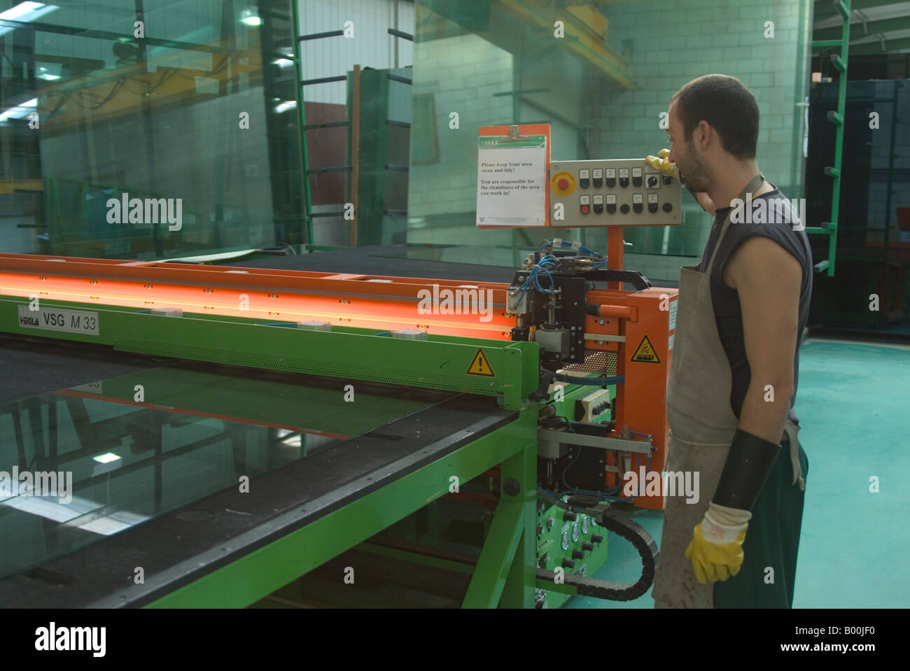 Lavoratore lFactory operando Taglio di vetro laminato macchina in fabbrica del vetro Foto Stock