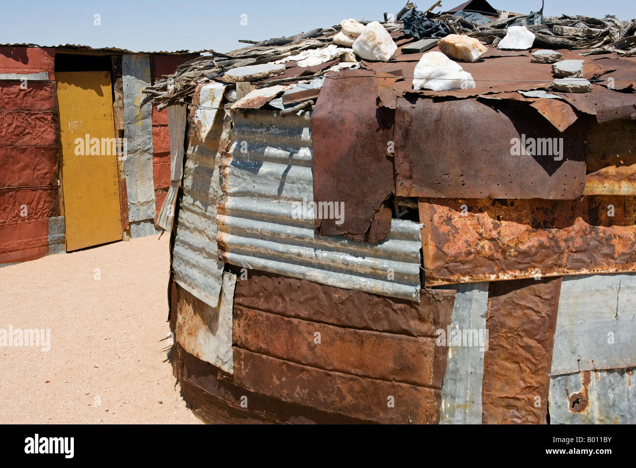 La Namibia, Namib Desert, Spitzkoppe. Capanne costruite al di fuori del cast off corregated lamiere di ferro in un Damara comunità agricole. Foto Stock