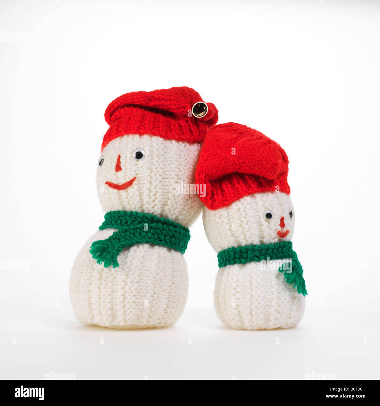 Pupazzi di neve appoggiato contro l'altra con cappucci rossi e sciarpe verde Foto Stock