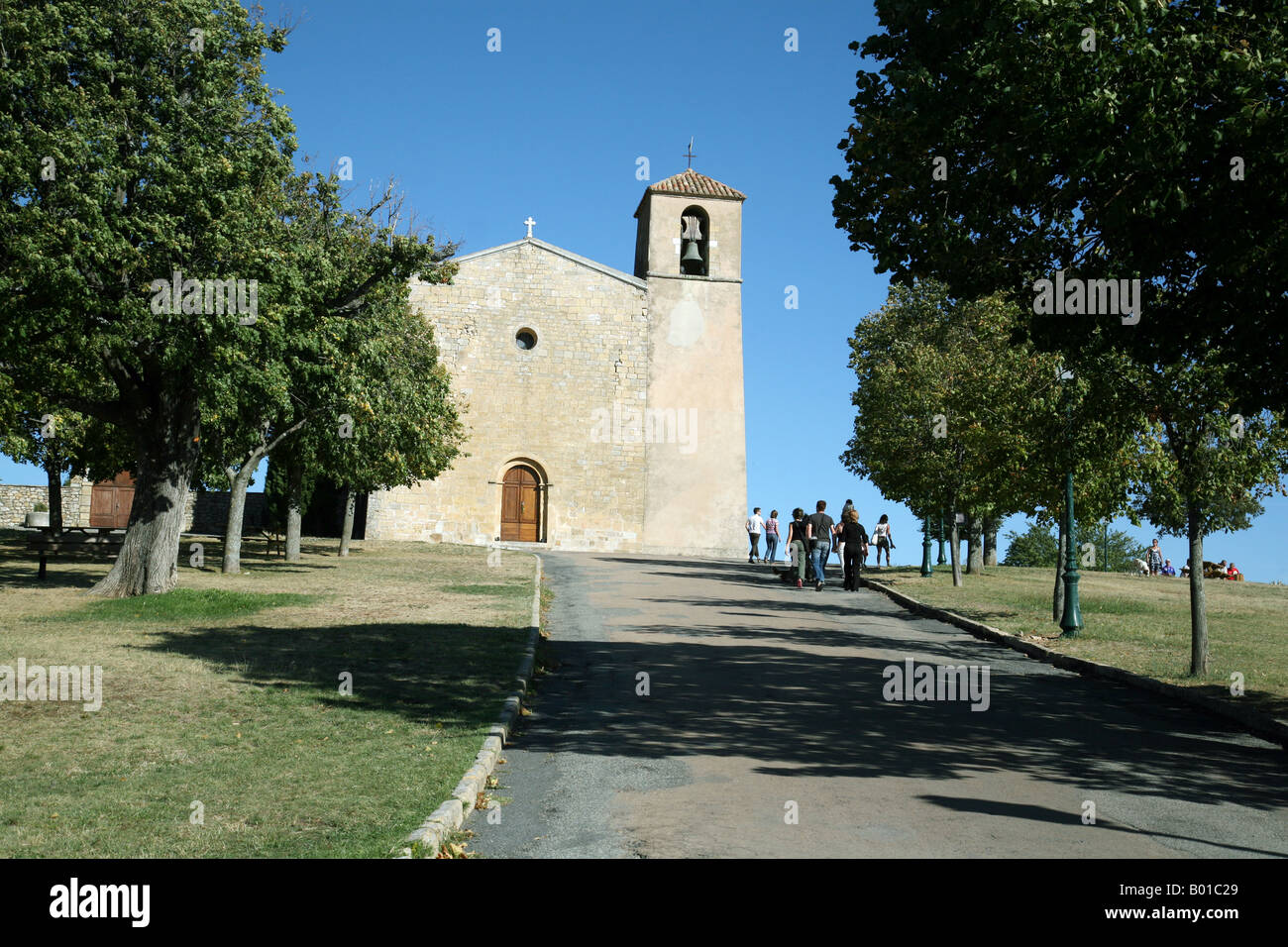 I turisti si avvicinano alla chiesa di St Denis nel villaggio di Tourtour, Provenza, Francia Foto Stock