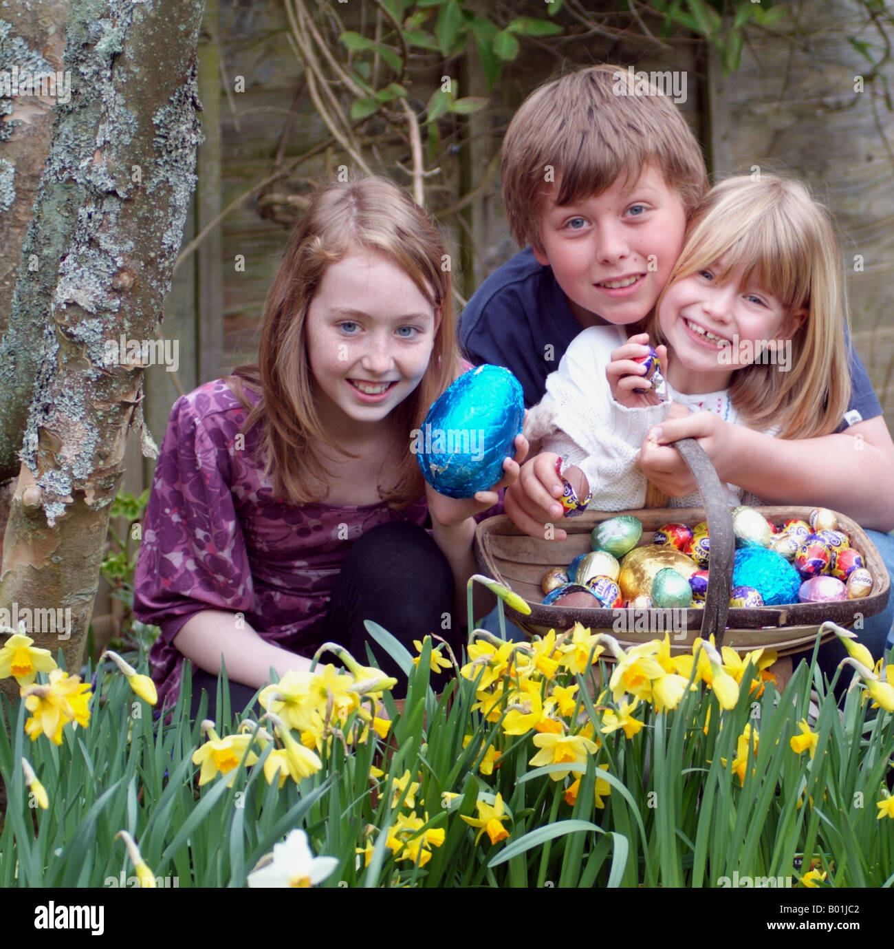 Uovo di Pasqua Caccia i bambini con un giardino Trug raccolta uova di cioccolato Foto Stock