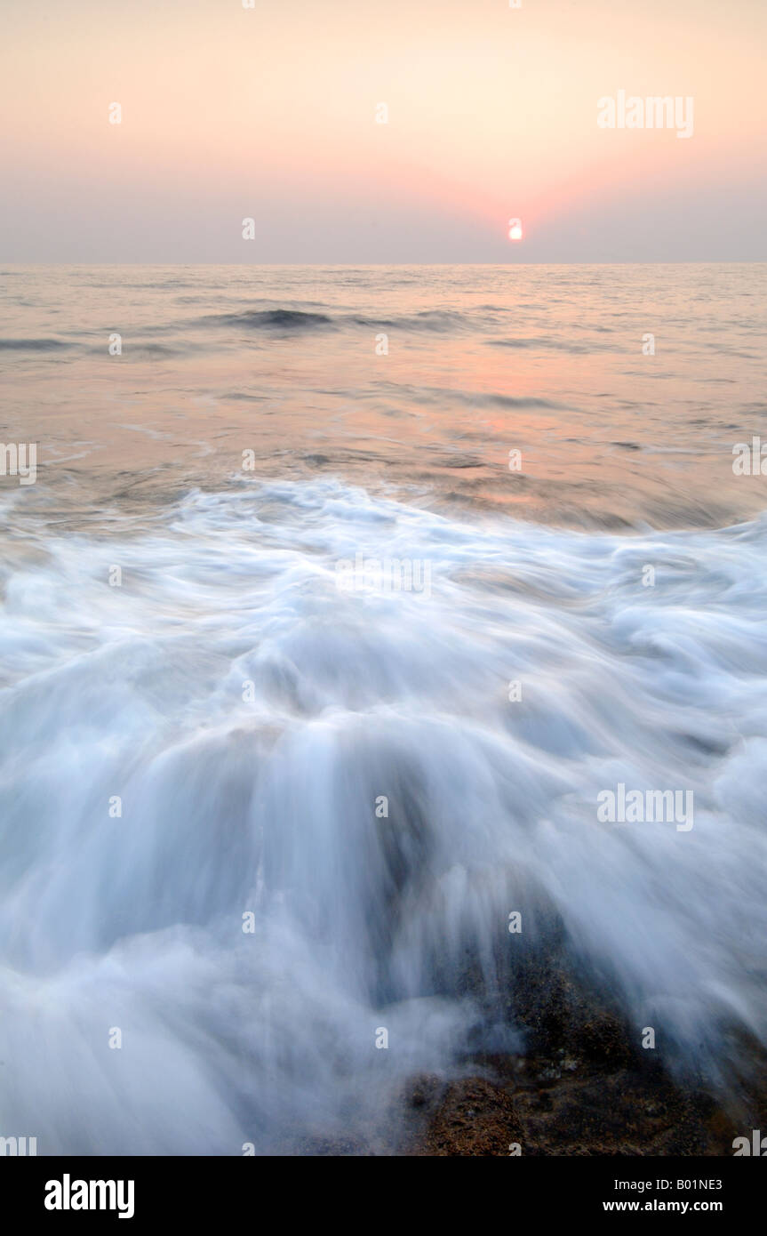 Tramonto sul mare di Lara mentre le onde giro su rocce umide resi lucidi dall'acqua Foto Stock