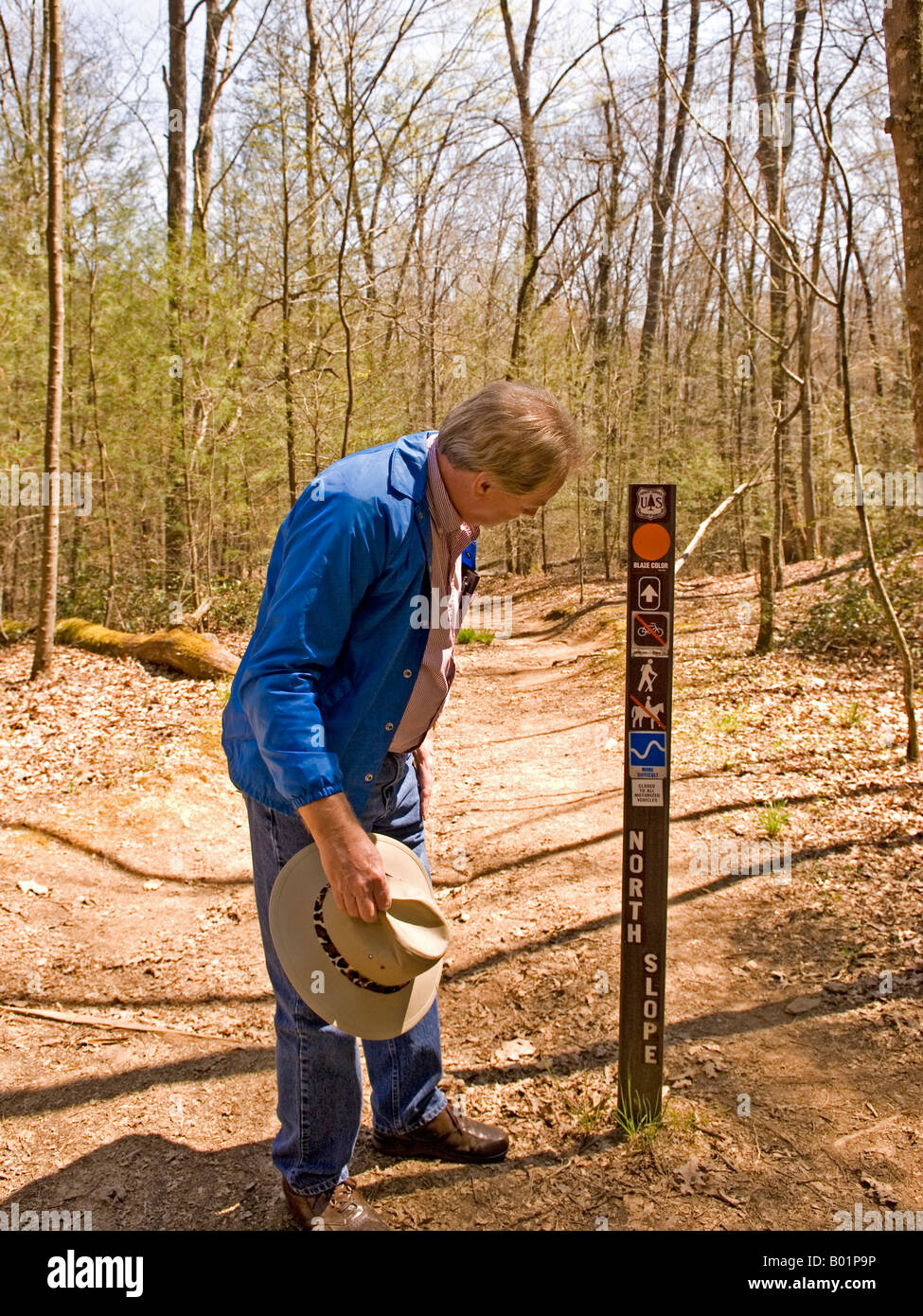 Uomo caucasico (50-55) guarda al segno sul sentiero al fiume Davidson campeggio nei pressi di Brevard North Carolina USA Foto Stock